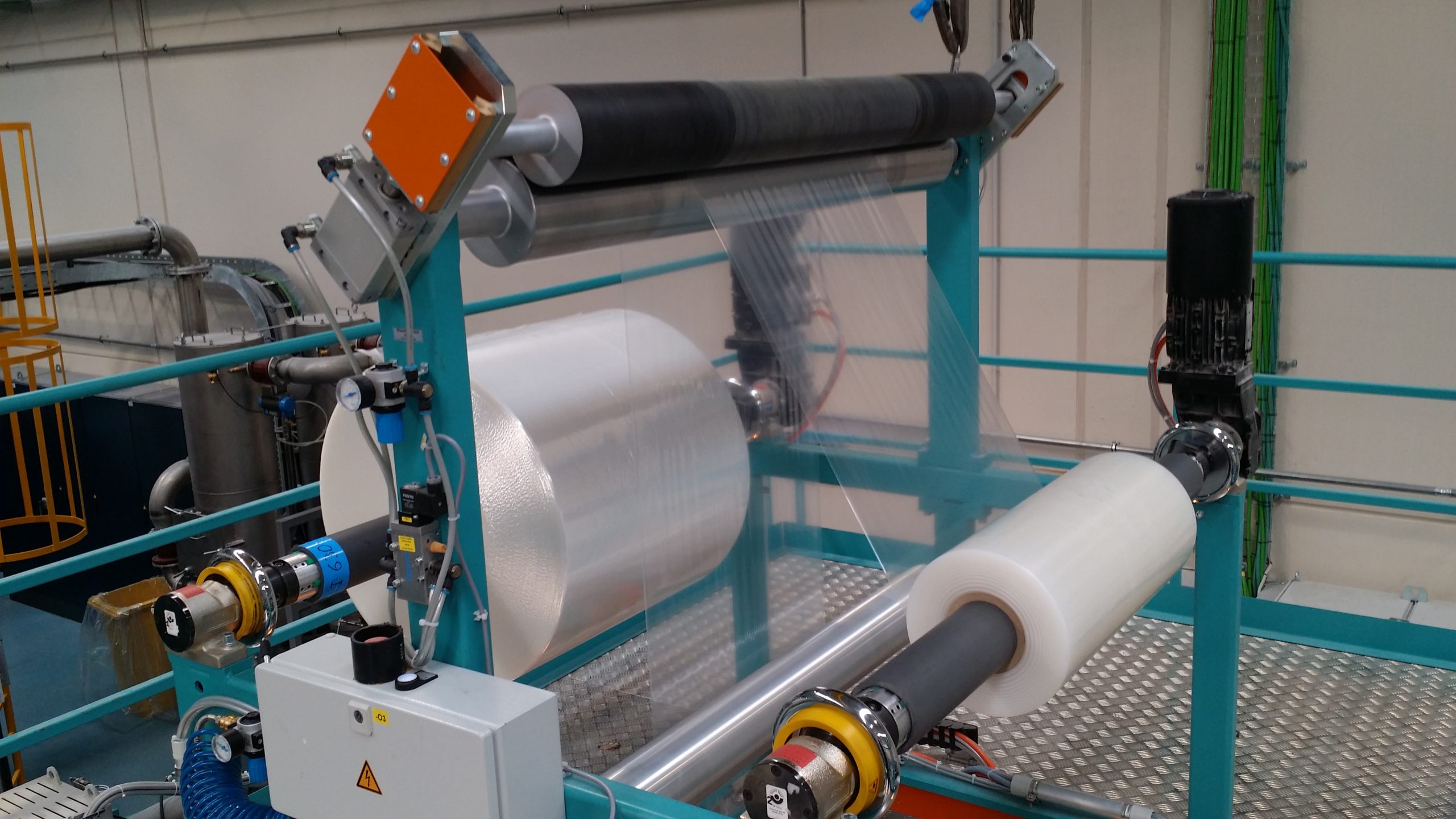 Extrusion coating lamination machine including a rubber roller for pressure and a metal roller for cooling and smoothing.